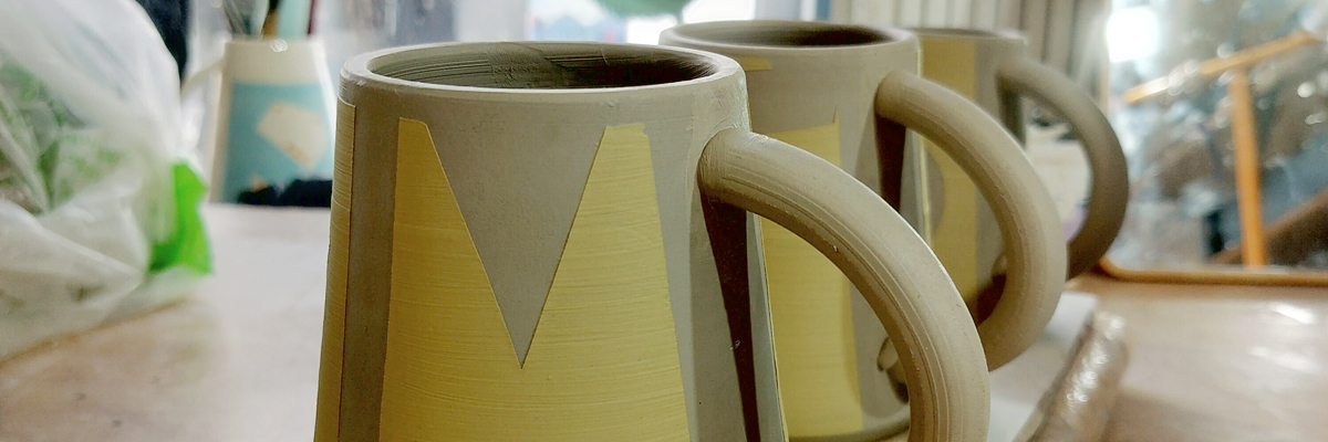 Three unfired mugs with a yellow pattern