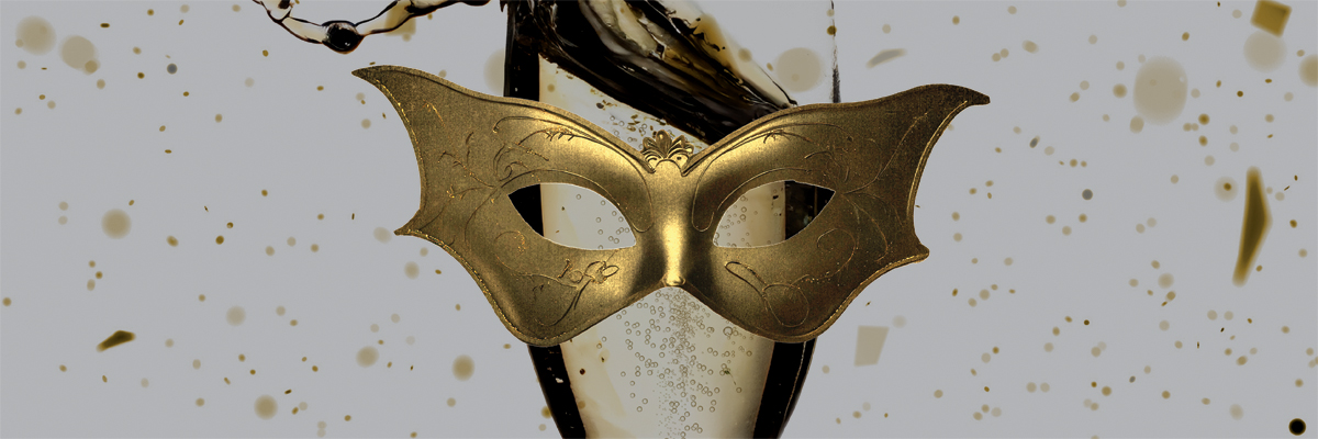 A champagne spills out of a champagne glass. A gold masquerade mask sits in front of the glass.