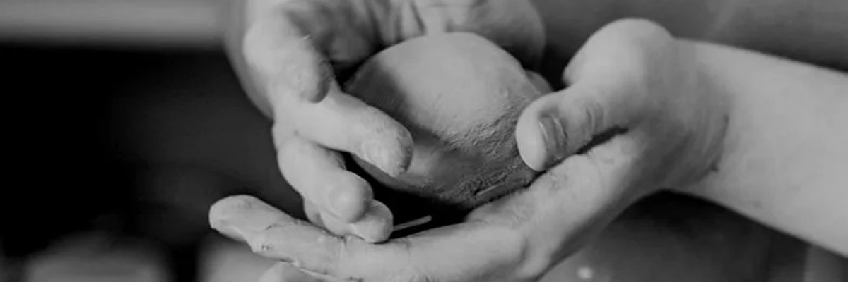 Black and white photo of someone shaping clay in their hands