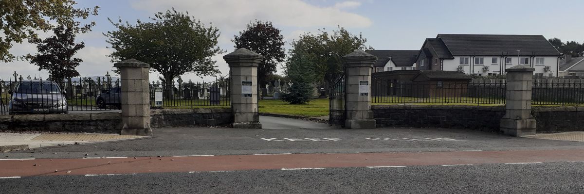 Blue sky with stone gates on the side of a road and trees in the background